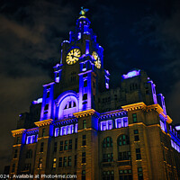 Buy canvas prints of Liverpool's iconic Royal Liver Building at night, illuminated with blue and yellow lights against a dark sky. by Man And Life