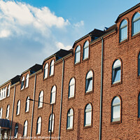 Buy canvas prints of Row of traditional brick buildings against a blue sky with clouds in York, UK. by Man And Life