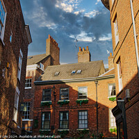 Buy canvas prints of Charming European alleyway with historic brick buildings and a glimpse of blue sky with clouds in York, UK. by Man And Life