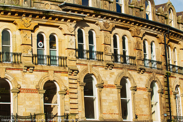 Vintage brick building facade with ornate windows and architectural details under a clear blue sky in Harrogate, England. Picture Board by Man And Life