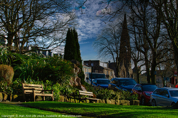 Tranquil urban park scene with benches and lush greenery, set against a backdrop of historic buildings and blue sky with wispy clouds in Harrogate, England. Picture Board by Man And Life