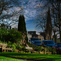 Buy canvas prints of Tranquil urban park scene with benches and lush greenery, set against a backdrop of historic buildings and blue sky with wispy clouds in Harrogate, England. by Man And Life