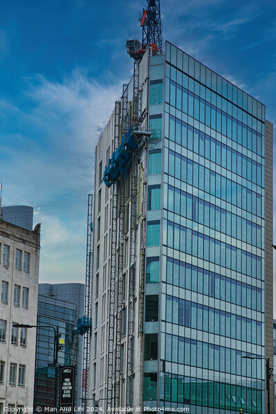 Modern glass building facade with reflections under a cloudy sky, surrounded by urban architecture in Leeds, UK. Picture Board by Man And Life
