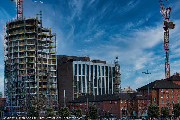 Urban construction site with cranes and developing high-rise building against a blue sky with wispy clouds in Liverpool, UK. Picture Board by Man And Life
