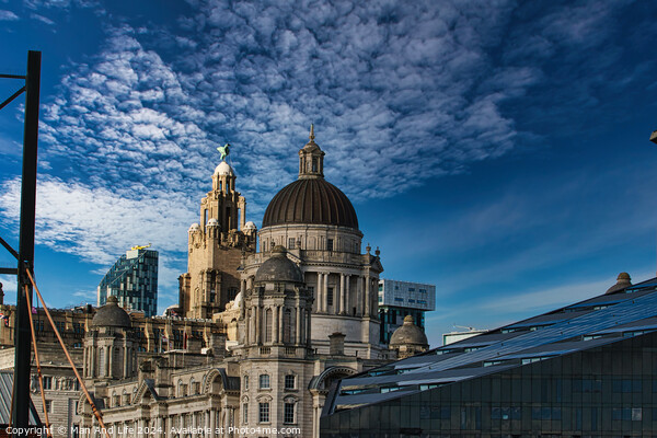 Liverpool's iconic waterfront buildings under a blue sky with wispy clouds. Picture Board by Man And Life