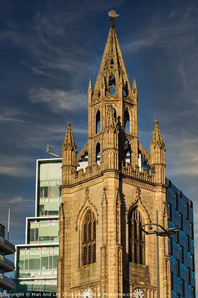 Gothic church spire against a blue sky with modern buildings in the background in Liverpool, UK. Picture Board by Man And Life