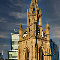 Buy canvas prints of Gothic church spire against a blue sky with modern buildings in the background in Liverpool, UK. by Man And Life