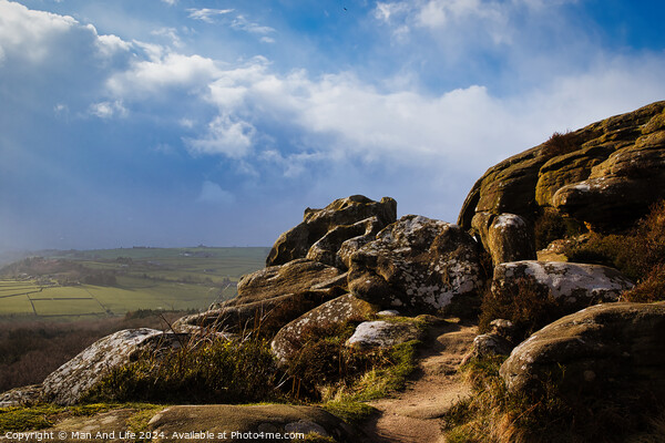 Majestic rocky landscape with sunlit grass under a blue sky with clouds at Brimham Rocks, in North Yorkshire Picture Board by Man And Life