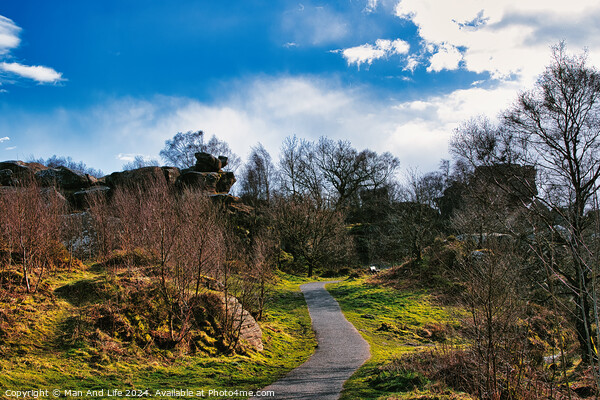 Scenic pathway through a lush park with rocky outcrops and vibrant blue sky with fluffy clouds at Brimham Rocks, in North Yorkshire Picture Board by Man And Life