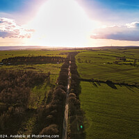 Buy canvas prints of Aerial view of a scenic country road at sunset with lush green fields and a dramatic sky in North Yorkshire. by Man And Life
