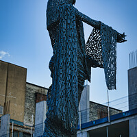 Buy canvas prints of Artistic metal sculpture of a humanoid figure against a clear blue sky, with urban buildings in the background in Leeds, UK. by Man And Life