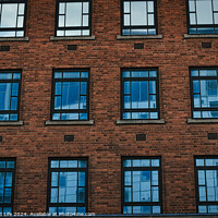 Buy canvas prints of Symmetrical brick building facade with rows of blue windows, urban architecture background in Leeds, UK. by Man And Life