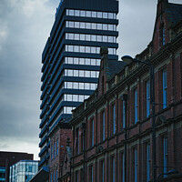 Buy canvas prints of Contrast of old and new architecture with a modern skyscraper towering behind a classic brick building under a cloudy sky in Leeds, UK. by Man And Life