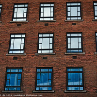 Buy canvas prints of Facade of a brick building with symmetrical windows reflecting the sky in Leeds, UK. by Man And Life