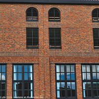 Buy canvas prints of Facade of a vintage brick building with rows of windows reflecting the sky, showcasing industrial architecture in York, North Yorkshire, England. by Man And Life