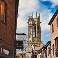 Buy canvas prints of Quaint urban street with festive bunting leading to a historic church tower under a blue sky with fluffy clouds in York, North Yorkshire, England. by Man And Life