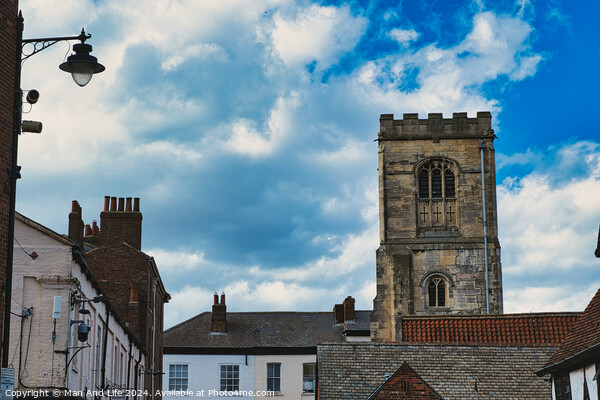Quaint European street with historic buildings and a prominent church tower under a dramatic sky with fluffy clouds in York, North Yorkshire, England. Picture Board by Man And Life