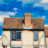 Buy canvas prints of Old European building with weathered facade and terracotta roof tiles against a backdrop of a vibrant blue sky with fluffy clouds in York, North Yorkshire, England. by Man And Life