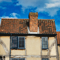 Buy canvas prints of Old European house with half-timbered walls and a red tiled roof against a blue sky with clouds. Vintage architecture with visible wear and character in York, North Yorkshire, England. by Man And Life