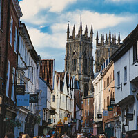 Buy canvas prints of Bustling street scene with pedestrians in a historic city center, featuring old buildings and a prominent Gothic cathedral under a cloudy sky in York, North Yorkshire, England. by Man And Life