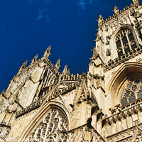 Buy canvas prints of Gothic cathedral facade against a clear blue sky, showcasing intricate architectural details and stone carvings, perfect for historical and travel themes in York, North Yorkshire, England. by Man And Life