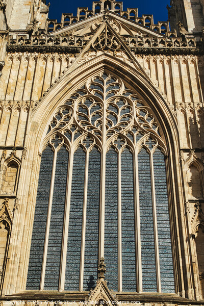 Gothic architecture detail of a cathedral window with intricate tracery and stained glass, set against a clear blue sky in York, North Yorkshire, England. Picture Board by Man And Life