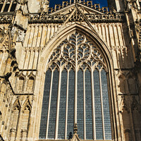 Buy canvas prints of Gothic architecture detail of a cathedral's facade, featuring a large stained glass window and ornate stone carvings under clear skies in York, North Yorkshire, England. by Man And Life