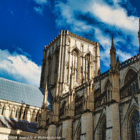 Buy canvas prints of Majestic Gothic cathedral against a blue sky with fluffy clouds, showcasing intricate architecture and historical grandeur in York, North Yorkshire, England. by Man And Life