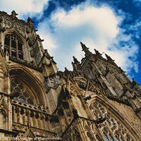 Buy canvas prints of Dramatic angle of a Gothic cathedral's facade with intricate stone carvings against a vivid blue sky with fluffy clouds, showcasing architectural grandeur and historical elegance in York, North Yorkshire, England. by Man And Life