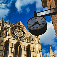 Buy canvas prints of Vintage street clock hanging with a gothic cathedral facade in the background, showcasing intricate architecture and a clear blue sky in York, North Yorkshire, England. by Man And Life