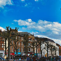 Buy canvas prints of Bustling city street scene with pedestrians, unique pruned trees under a blue sky with clouds, and historic buildings, capturing the essence of urban life in York, North Yorkshire, England. by Man And Life