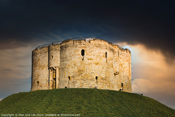 Dramatic sky over an ancient stone fortress atop a lush green hill, symbolizing historical strength and medieval architecture in York, North Yorkshire, England. Picture Board by Man And Life