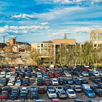 Buy canvas prints of Urban parking lot filled with cars on a sunny day, with city buildings in the background and a clear blue sky overhead in York, North Yorkshire, England. by Man And Life