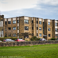 Buy canvas prints of Modern residential apartment buildings with parked cars in front, behind a stone wall with a lush green lawn in the foreground. Urban living concept in Harrogate, North Yorkshire. by Man And Life