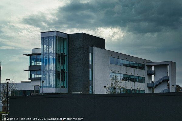 Modern office building against a dramatic cloudy sky, showcasing contemporary architecture with a mix of glass and concrete elements. Picture Board by Man And Life