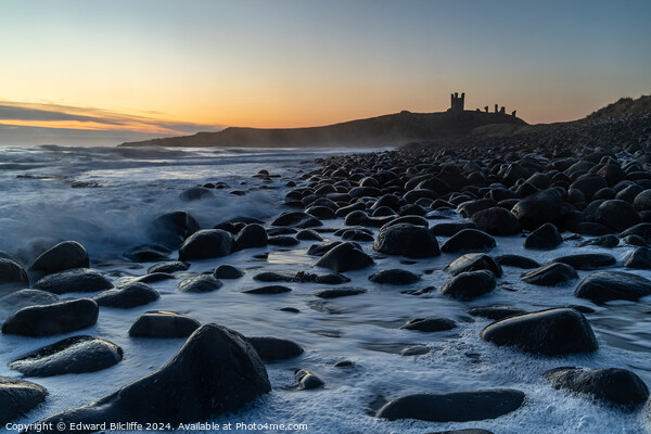 Boulder Beach and Dunstanburgh Castle at dawn Picture Board by Edward Bilcliffe