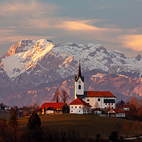 Buy canvas prints of Prezganje church with snowy Kamnik Alps in the bac by Ian Middleton
