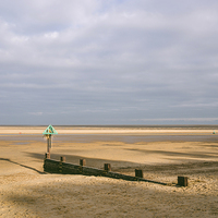 Buy canvas prints of Green groyne marker and sunlit beach under a heavy by Liam Grant