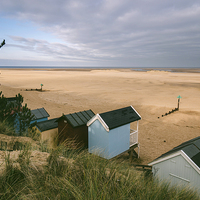 Buy canvas prints of Beach huts and sunlit view out to sea. by Liam Grant