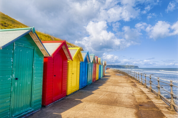 Vibrant Beach Huts Adorning Whitby Beachfront Picture Board by Derek Beattie
