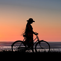 Buy canvas prints of Silhouette Of Girl And Bike At Sunset Near The Sea by Maggie McCall