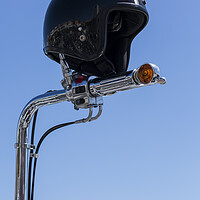 Buy canvas prints of Open face crash helmet on handlebars of a motorcycle against a blue sky by Phil Crean
