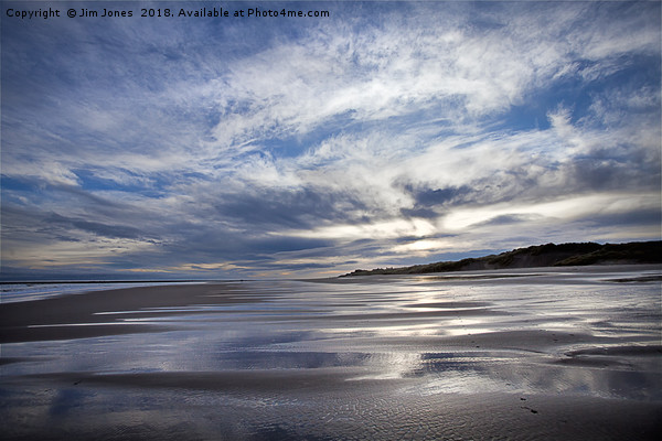 Cloudy blue sky reflected in the wet sand at Druri Picture Board by Jim Jones