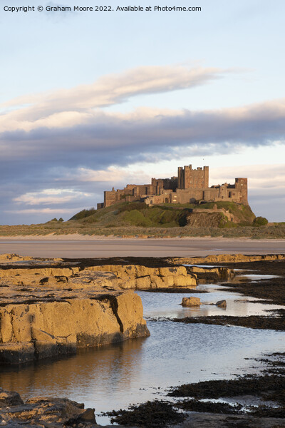 Bamburgh Castle from Harkness Rocks sunset vert Picture Board by Graham Moore